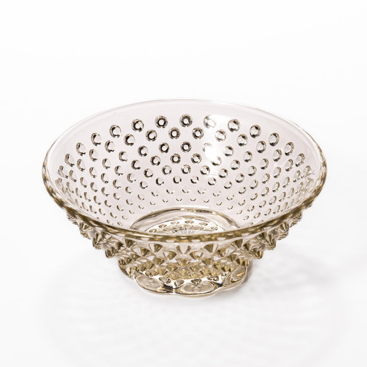 Amber glass dessert bowl and saucer with raised dots and starburst base, perfect for serving refined sweets.