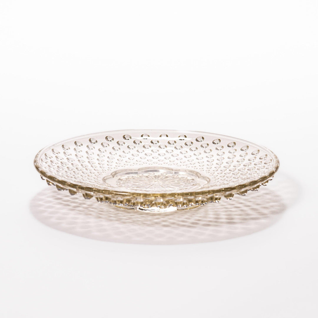 Amber glass dessert bowl and saucer with raised dots and starburst base, perfect for serving refined sweets.