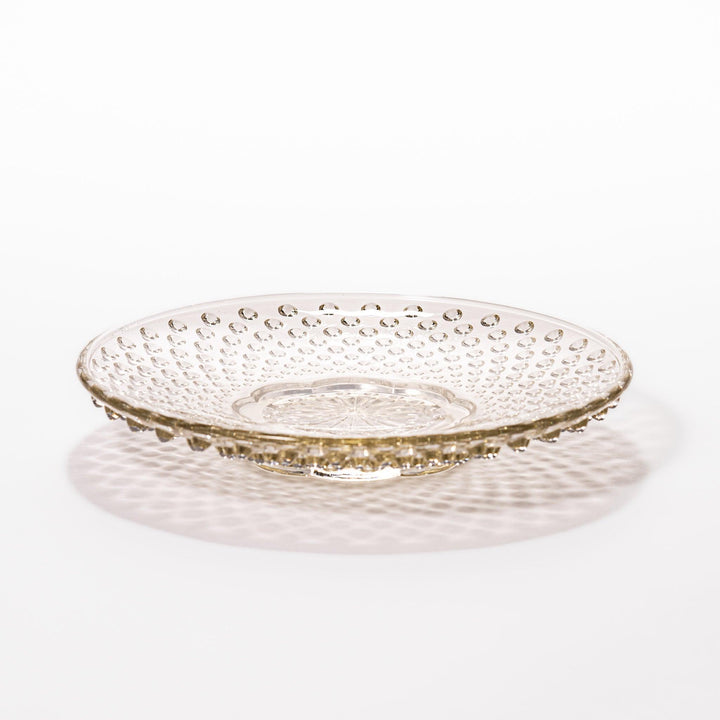 Amber glass dessert bowl and saucer with raised dots and starburst base, perfect for serving refined sweets.