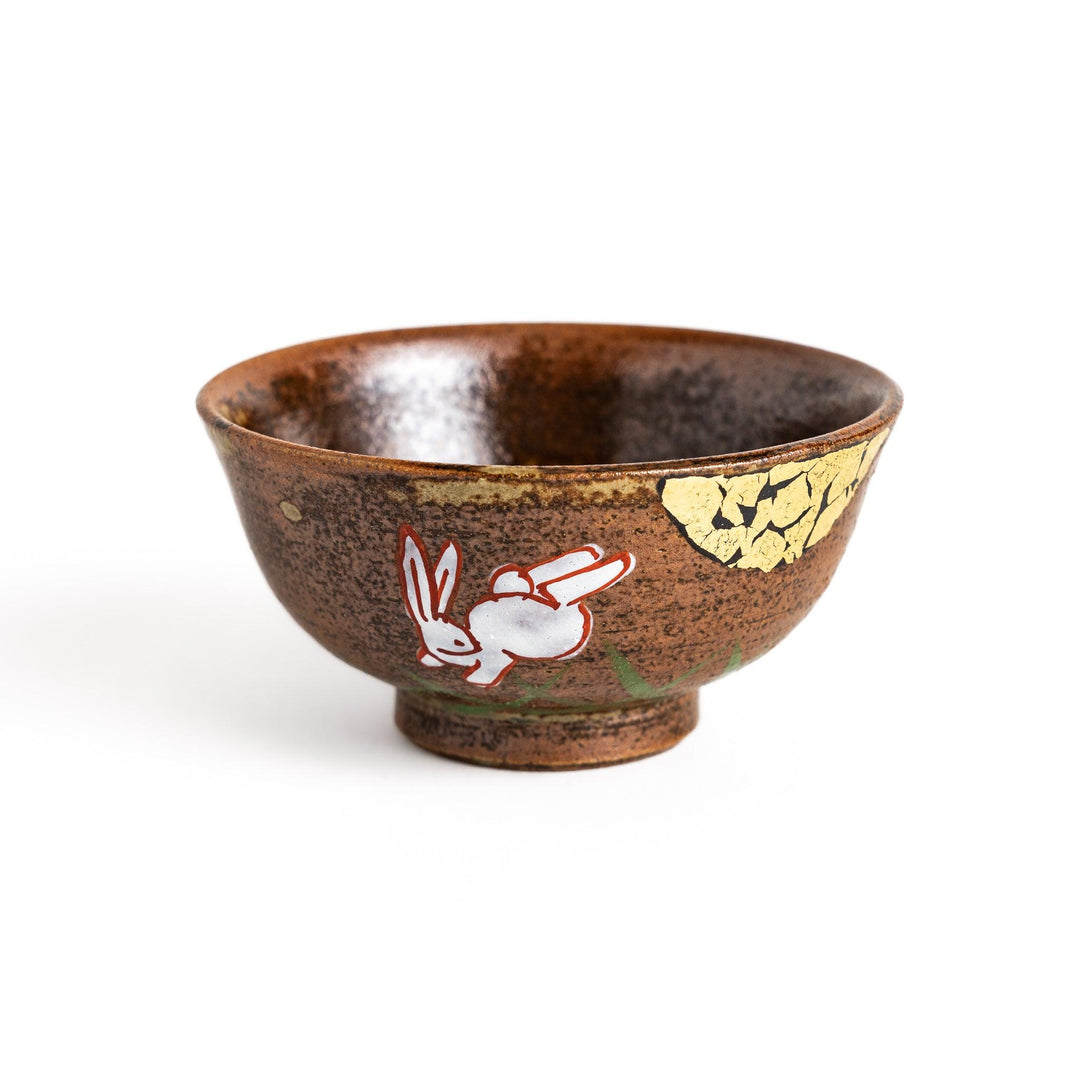 Brown ceramic sake set with rabbit and moon design including carafe and cups on tray for sharing.