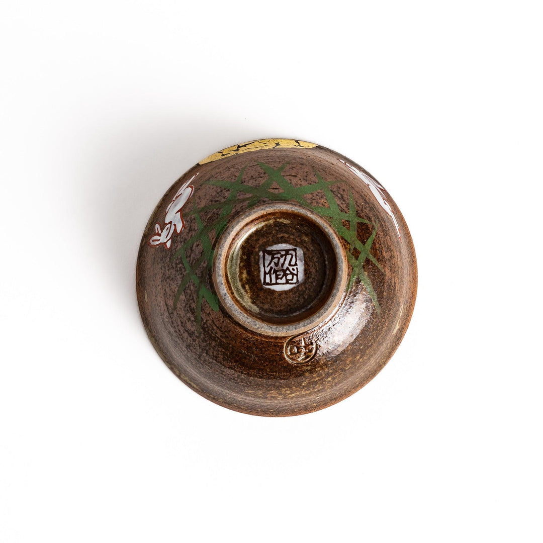 Brown ceramic sake set with rabbit and moon design including carafe and cups on tray for sharing.