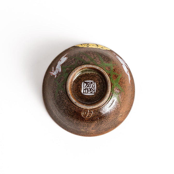 Brown ceramic sake set with rabbit and moon design including carafe and cups on tray for sharing.