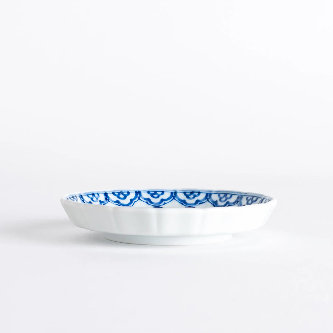 A small round ceramic plate with a blue dragon and Mount Fuji design, bordered with intricate patterns.