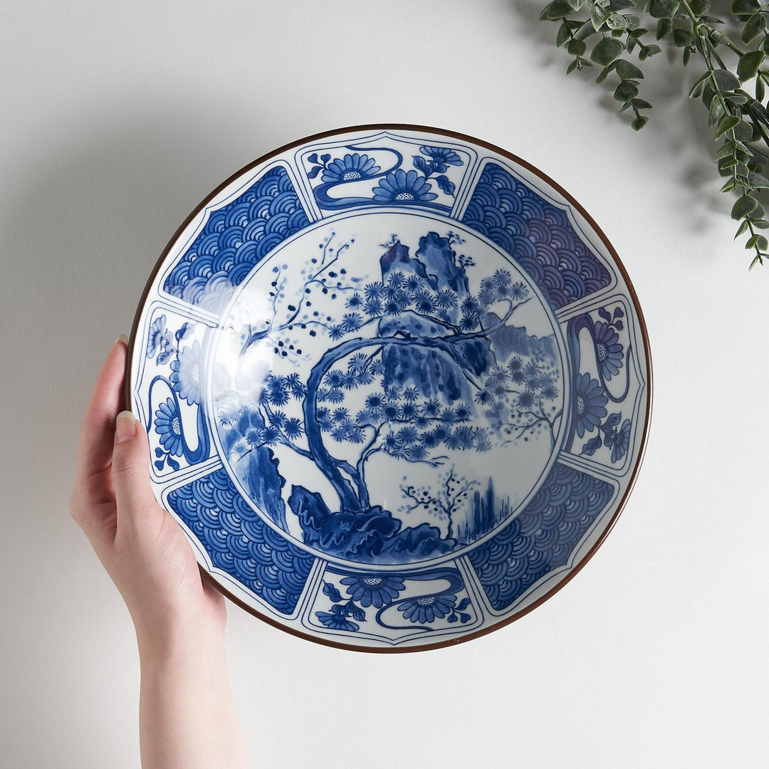 Bowl with dark blue exterior and white interior featuring blue floral wave and landscape motifs inside.