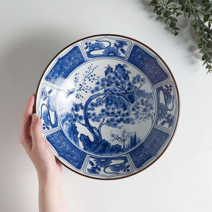 Bowl with dark blue exterior and white interior featuring blue floral wave and landscape motifs inside.