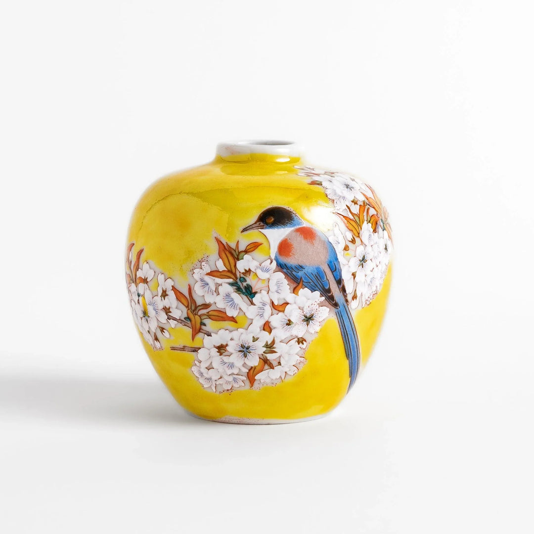 Yellow vase with cherry blossoms and colorful bird design bringing a bright touch of spring to decor.