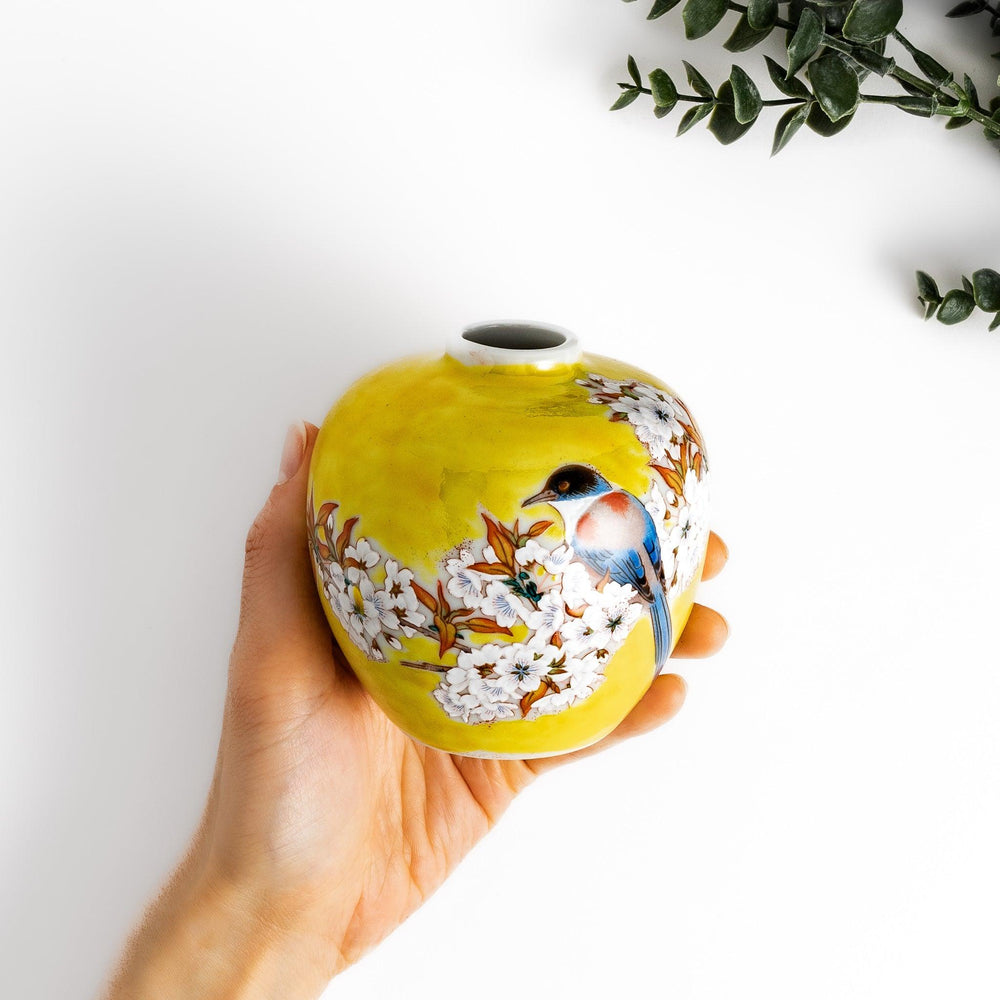 Yellow vase with cherry blossoms and colorful bird design bringing a bright touch of spring to decor.