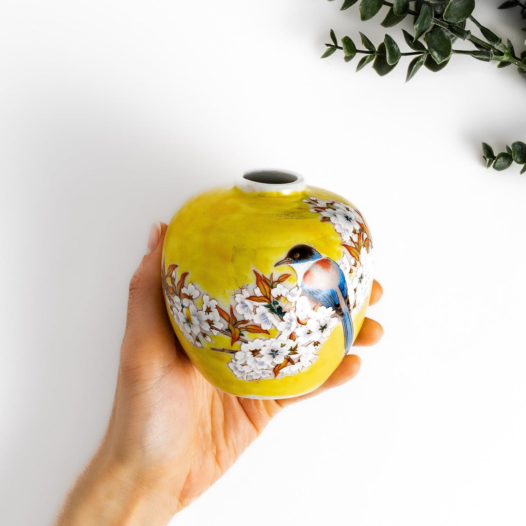 Yellow vase with cherry blossoms and colorful bird design bringing a bright touch of spring to decor.