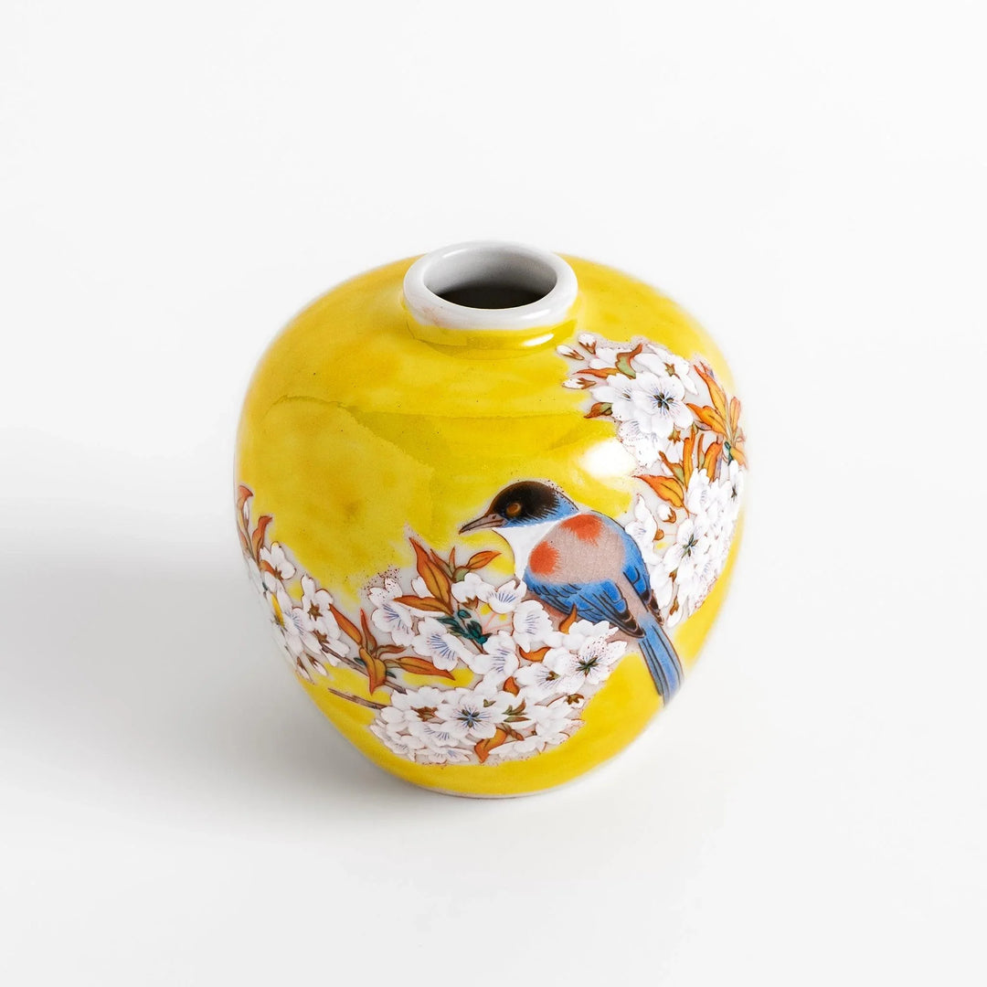 Yellow vase with cherry blossoms and colorful bird design bringing a bright touch of spring to decor.