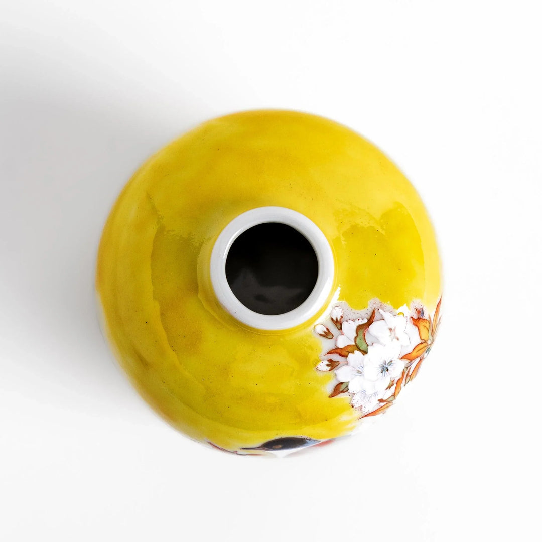 Yellow vase with cherry blossoms and colorful bird design bringing a bright touch of spring to decor.