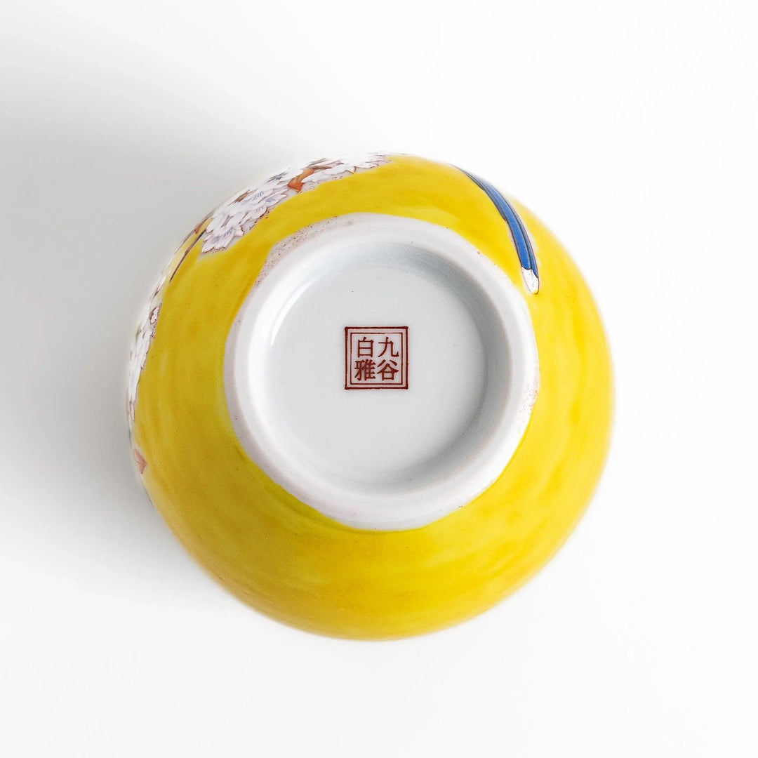 Yellow vase with cherry blossoms and colorful bird design bringing a bright touch of spring to decor.