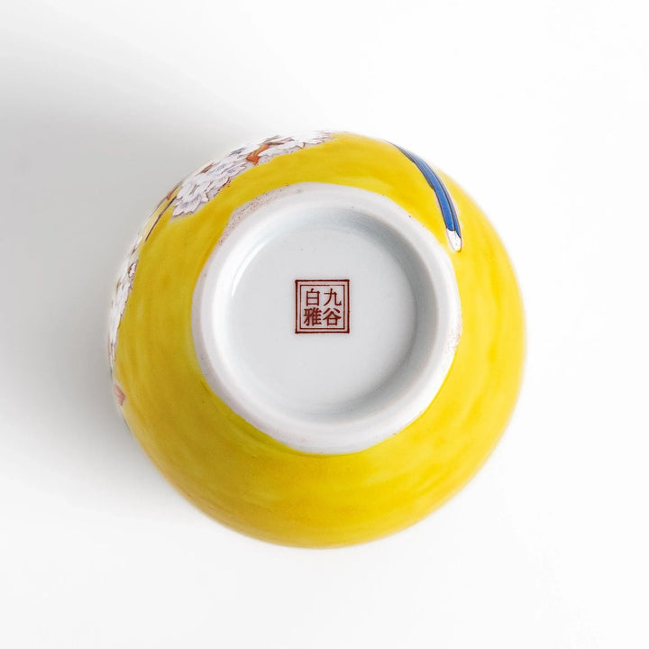 Yellow vase with cherry blossoms and colorful bird design bringing a bright touch of spring to decor.