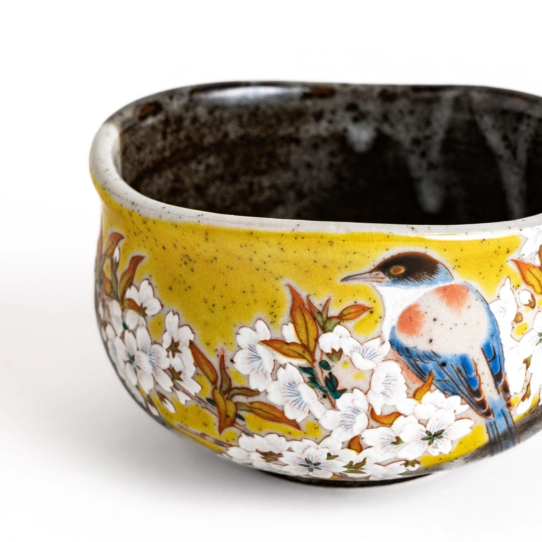 Yellow matcha bowl with bird and flowering branch design ideal for preparing and enjoying matcha tea.