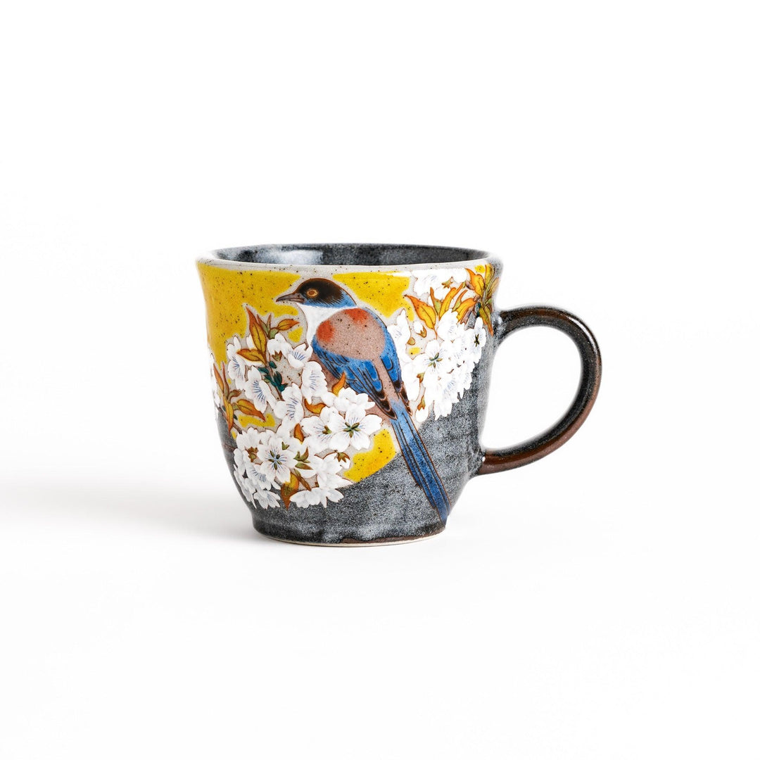 Ceramic mug with bird and flowering branch on yellow background perfect for daily coffee or tea.