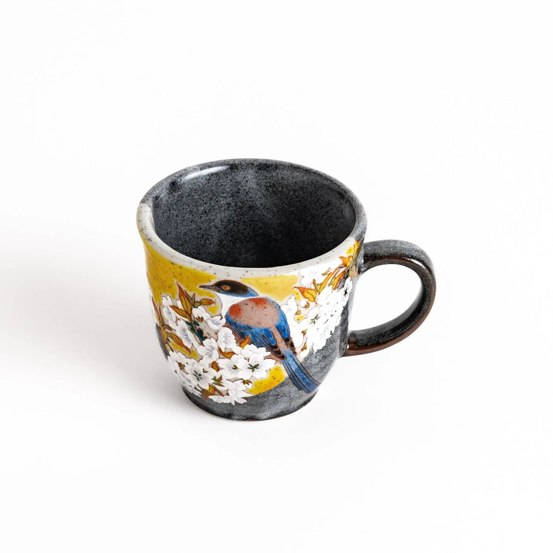 Ceramic mug with bird and flowering branch on yellow background perfect for daily coffee or tea.