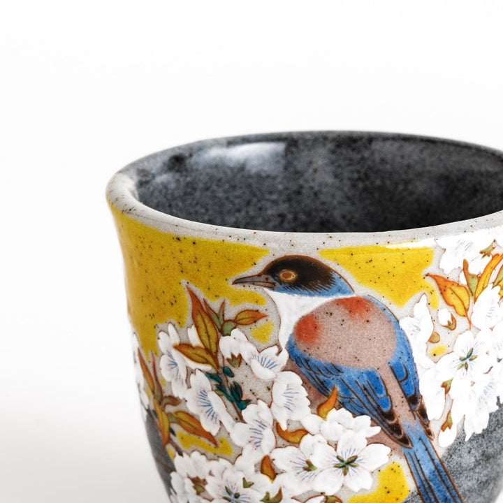 Ceramic mug with bird and flowering branch on yellow background perfect for daily coffee or tea.