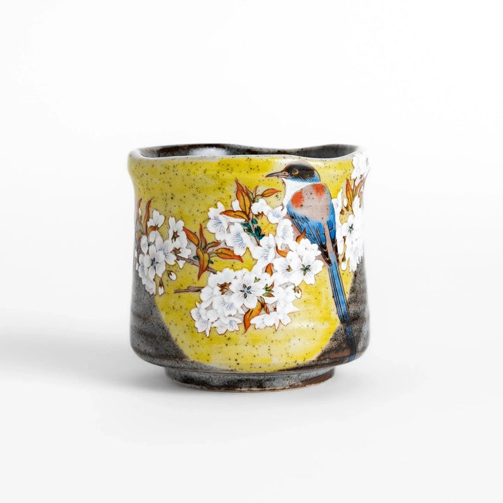 Tea Cup featuring a bird perched on blooming sakura flowers, set against a yellow and gray background.