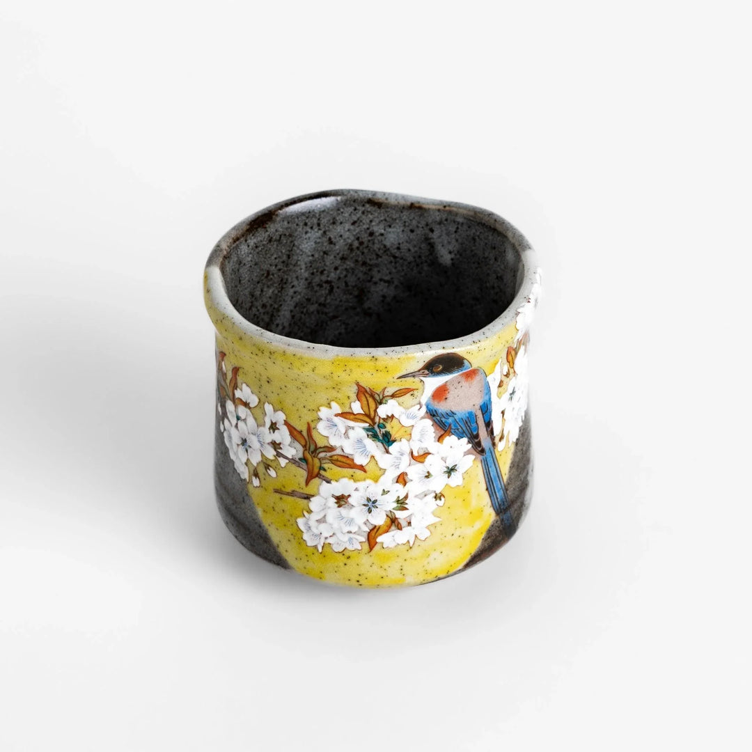 Tea Cup featuring a bird perched on blooming sakura flowers, set against a yellow and gray background.