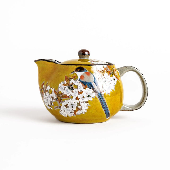 Yellow ceramic teapot with bird and flower motif and smooth sheen perfect for serving Japanese tea.