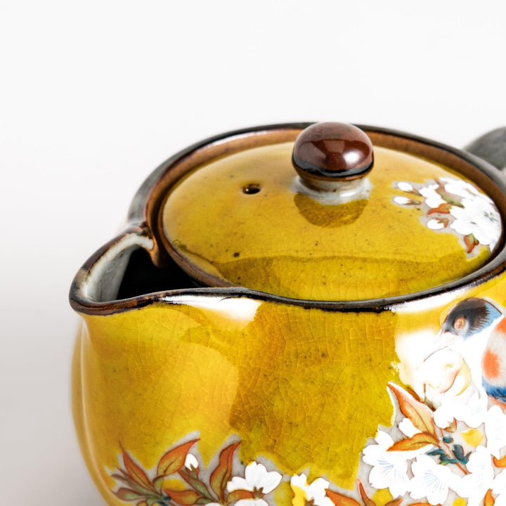 Yellow ceramic teapot with bird and flower motif and smooth sheen perfect for serving Japanese tea.