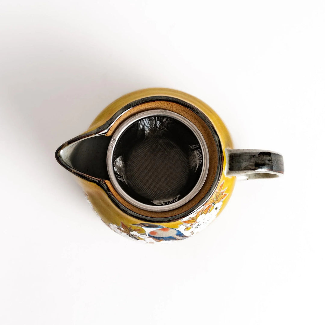 Yellow ceramic teapot with bird and flower motif and smooth sheen perfect for serving Japanese tea.