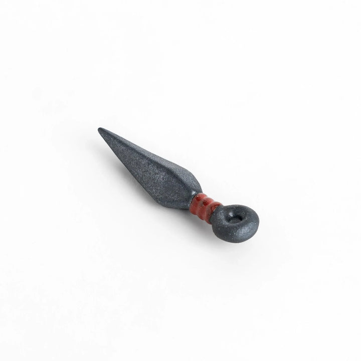 Ninja blade shaped metallic chopstick rest with red accent adding bold and unique touch to dining.
