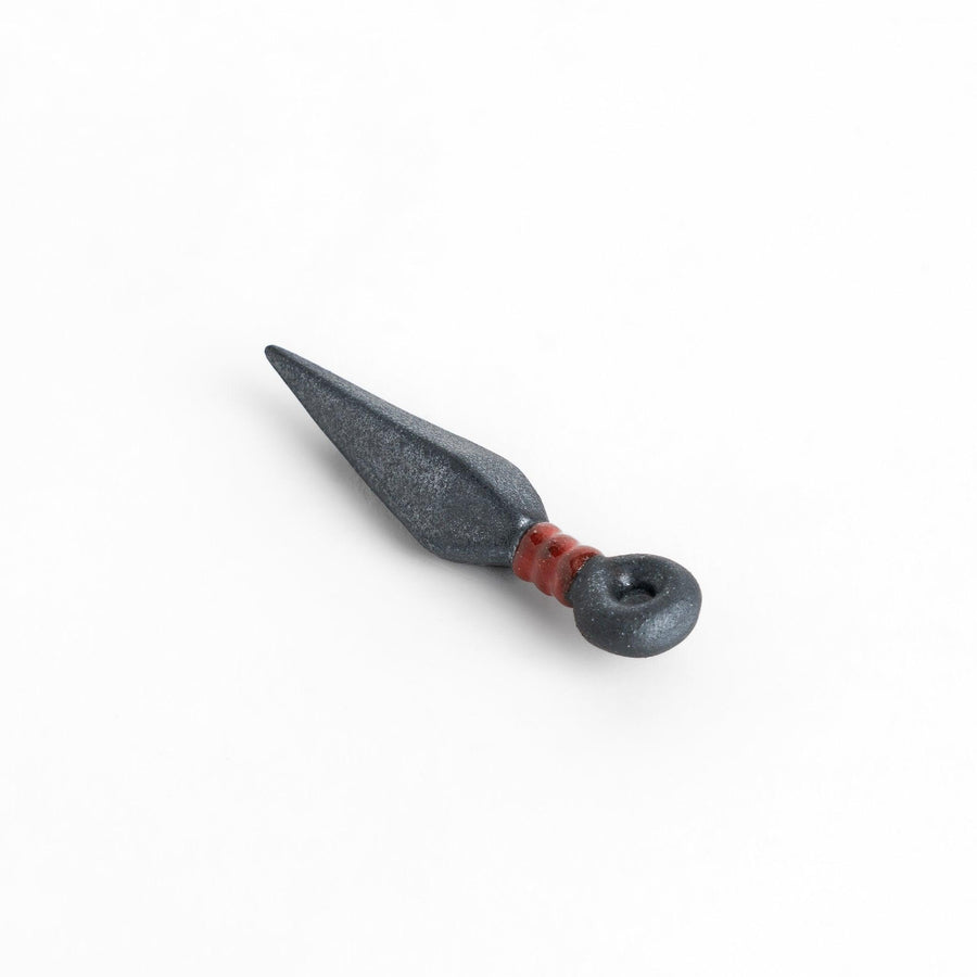 Ninja blade shaped metallic chopstick rest with red accent adding bold and unique touch to dining.