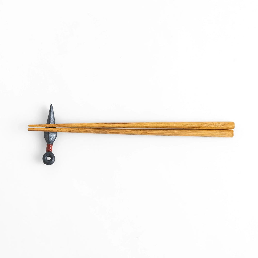 Ninja blade shaped metallic chopstick rest with red accent adding bold and unique touch to dining.