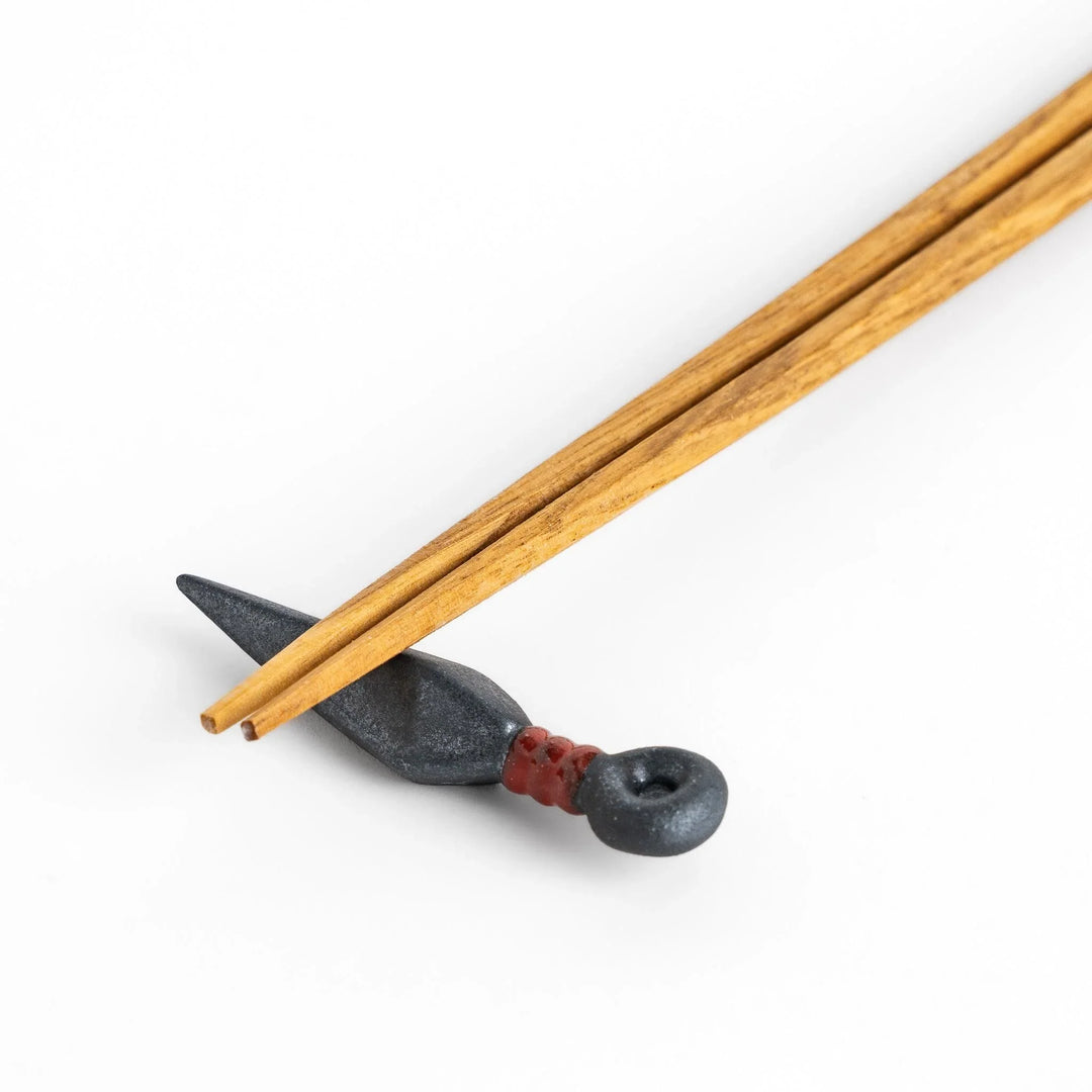 Ninja blade shaped metallic chopstick rest with red accent adding bold and unique touch to dining.