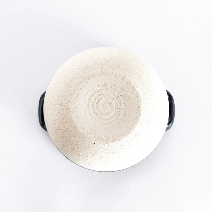 Bottom view of the donabe, showing its white base and sturdy, flat bottom surface.