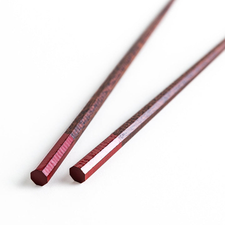 Lacquered chopsticks pair with octagonal minimalist design for sleek functional dining in green or red.