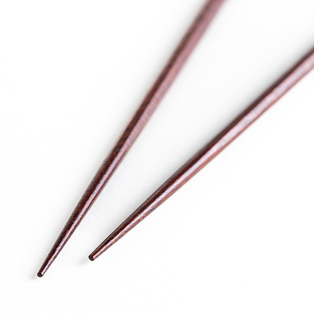 Lacquered chopsticks pair with octagonal minimalist design for sleek functional dining in green or red.