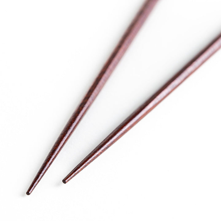 Lacquered chopsticks pair with octagonal minimalist design for sleek functional dining in green or red.