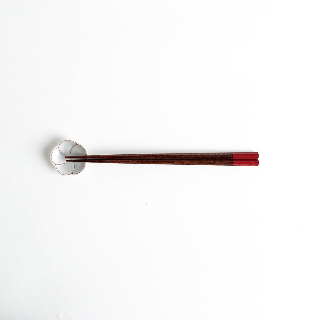Lacquered chopsticks pair with octagonal minimalist design for sleek functional dining in green or red.