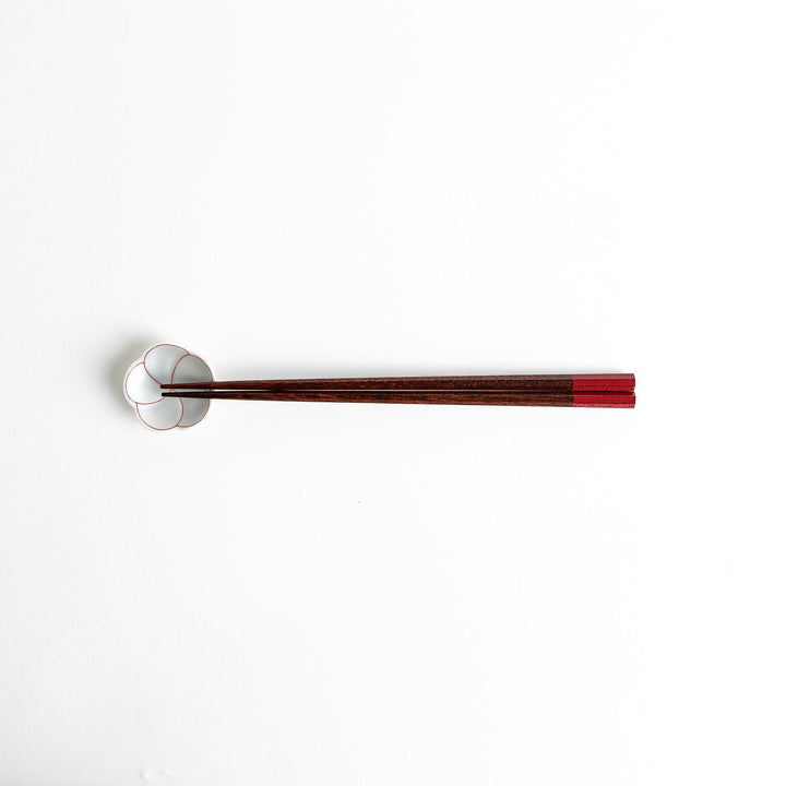 Lacquered chopsticks pair with octagonal minimalist design for sleek functional dining in green or red.