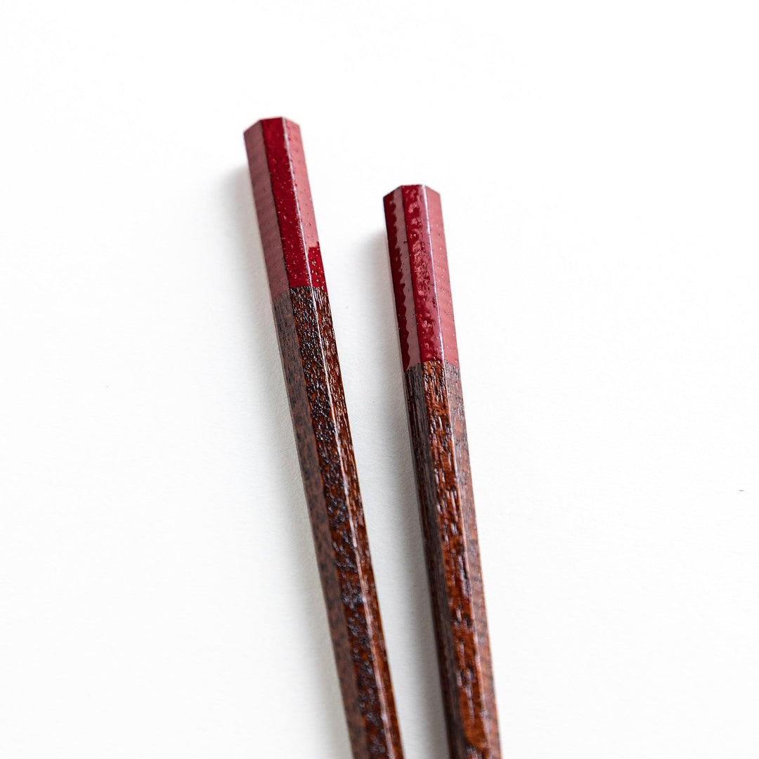 Lacquered chopsticks pair with octagonal minimalist design for sleek functional dining in green or red.