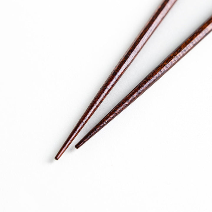 Lacquered chopsticks pair with octagonal minimalist design for sleek functional dining in green or red.