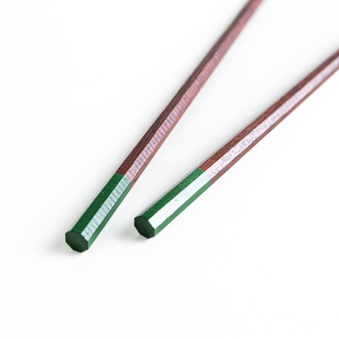 Lacquered chopsticks pair with octagonal minimalist design for sleek functional dining in green or red.