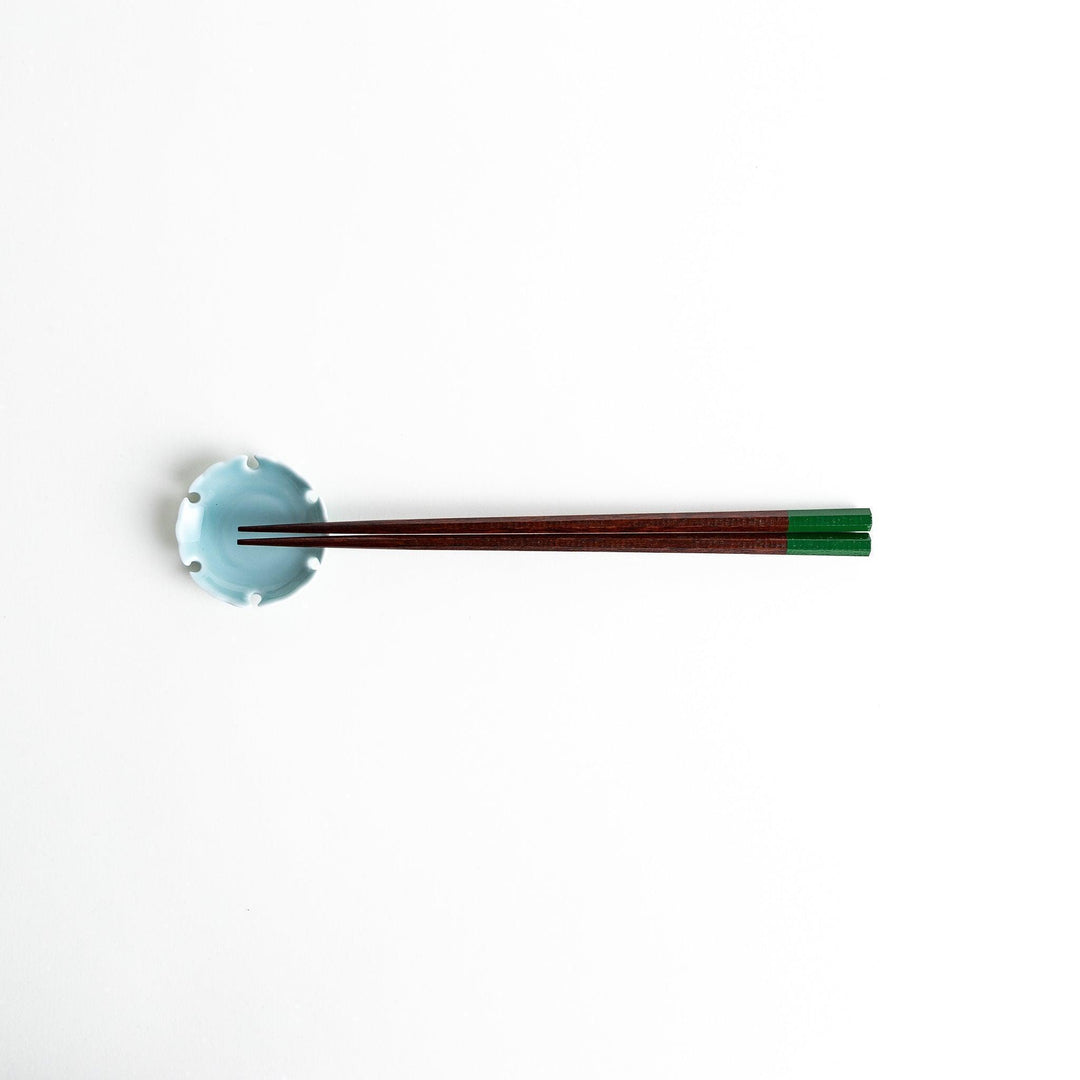 Lacquered chopsticks pair with octagonal minimalist design for sleek functional dining in green or red.