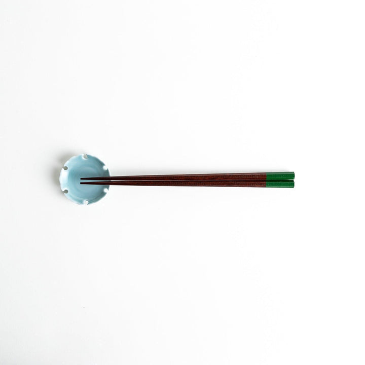 Lacquered chopsticks pair with octagonal minimalist design for sleek functional dining in green or red.