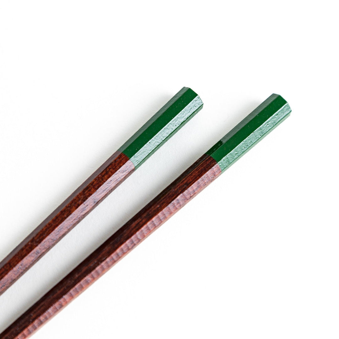 Lacquered chopsticks pair with octagonal minimalist design for sleek functional dining in green or red.
