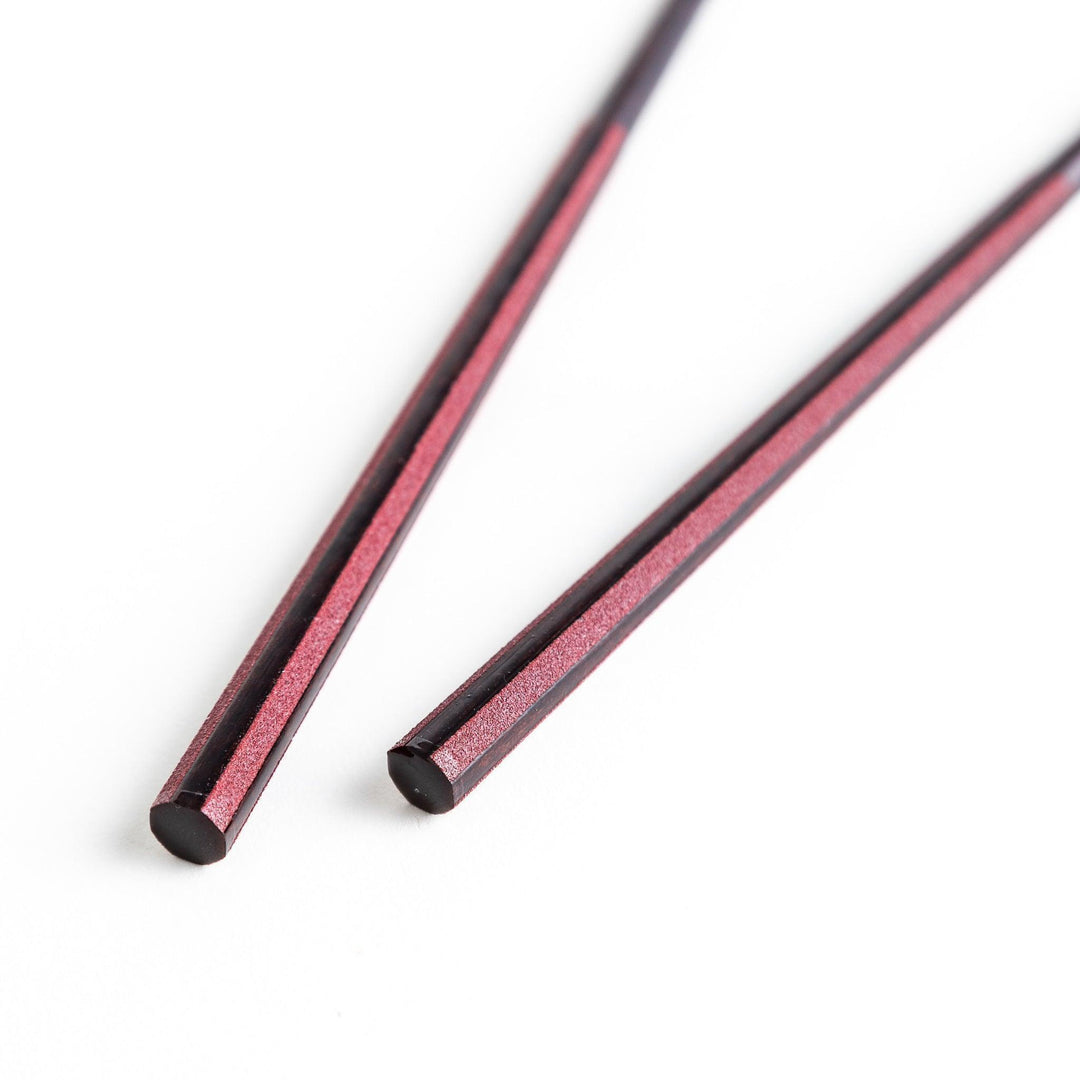 Octagonal wooden chopsticks with a brown tone, finished with a textured grain. Available in red or black.