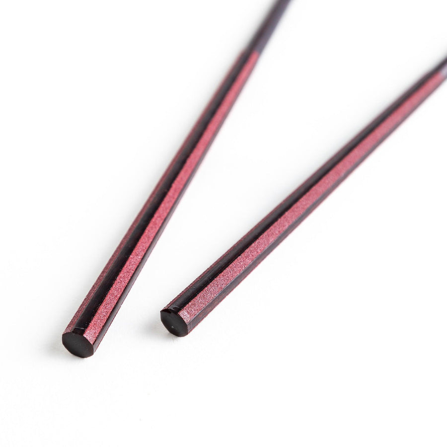 Octagonal wooden chopsticks with a brown tone, finished with a textured grain. Available in red or black.