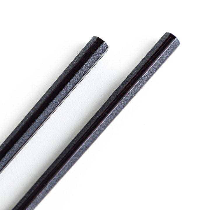 Octagonal wooden chopsticks with a brown tone, finished with a textured grain. Available in red or black.