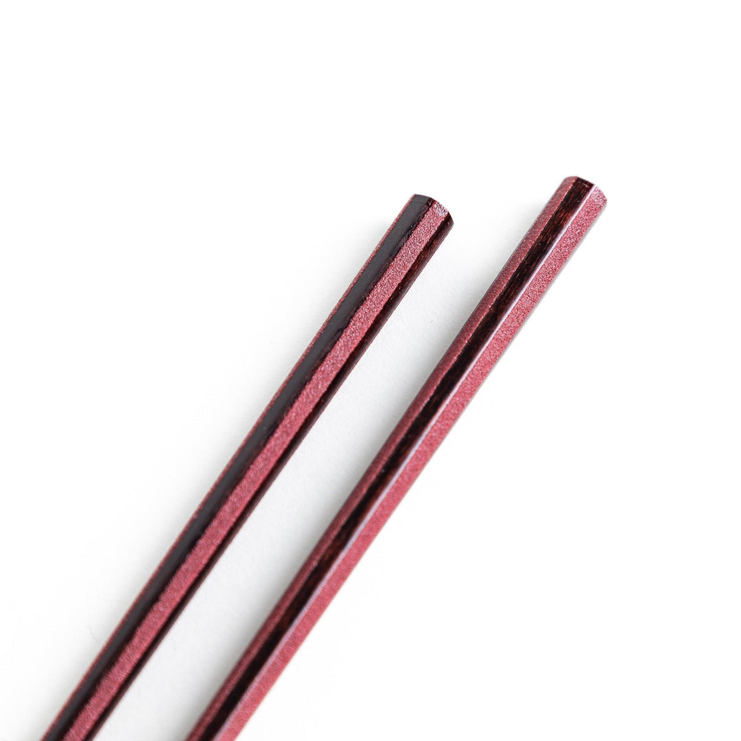 Octagonal wooden chopsticks with a brown tone, finished with a textured grain. Available in red or black.