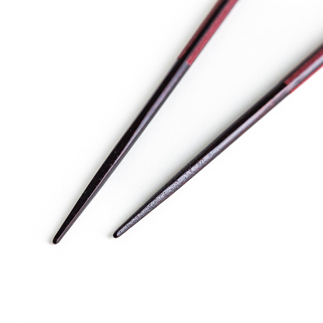 Octagonal wooden chopsticks with a brown tone, finished with a textured grain. Available in red or black.