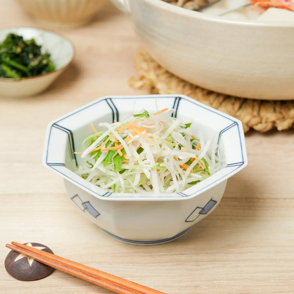 Japanese porcelain salad bowl with octagonal shape and blue geometric design, serving fresh daikon and carrot salad.