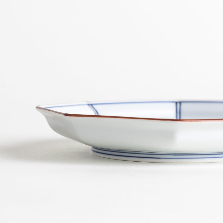 An octagonal porcelain dessert plate with a minimalist grid pattern.