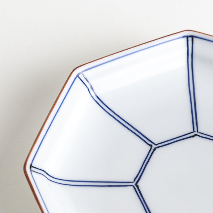An octagonal porcelain dessert plate with a minimalist grid pattern.