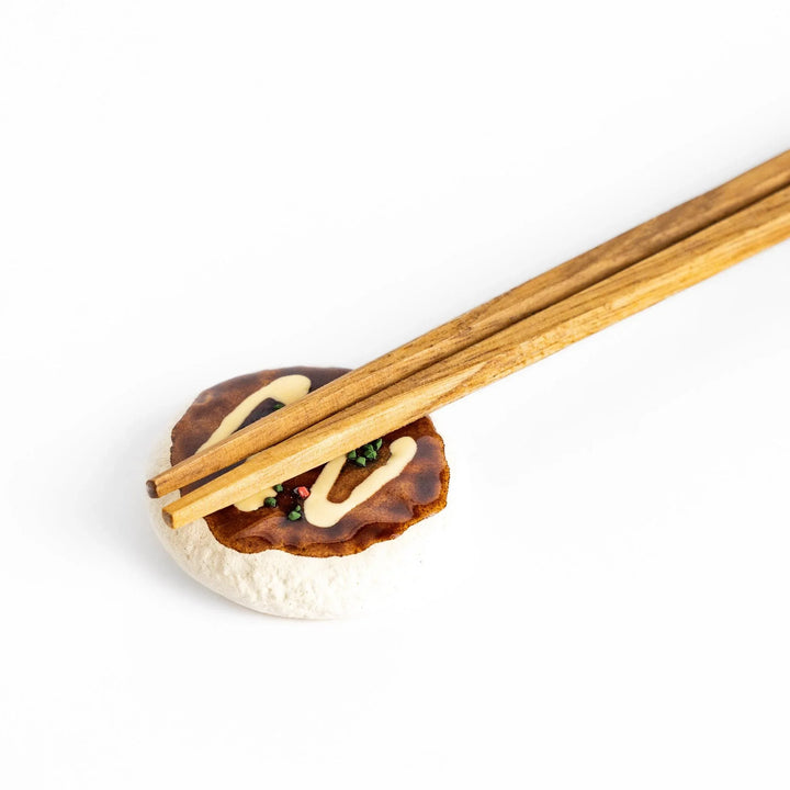 Fun Okonomiyaki-shaped chopstick rest with realistic details, including drizzled sauce and colorful toppings.